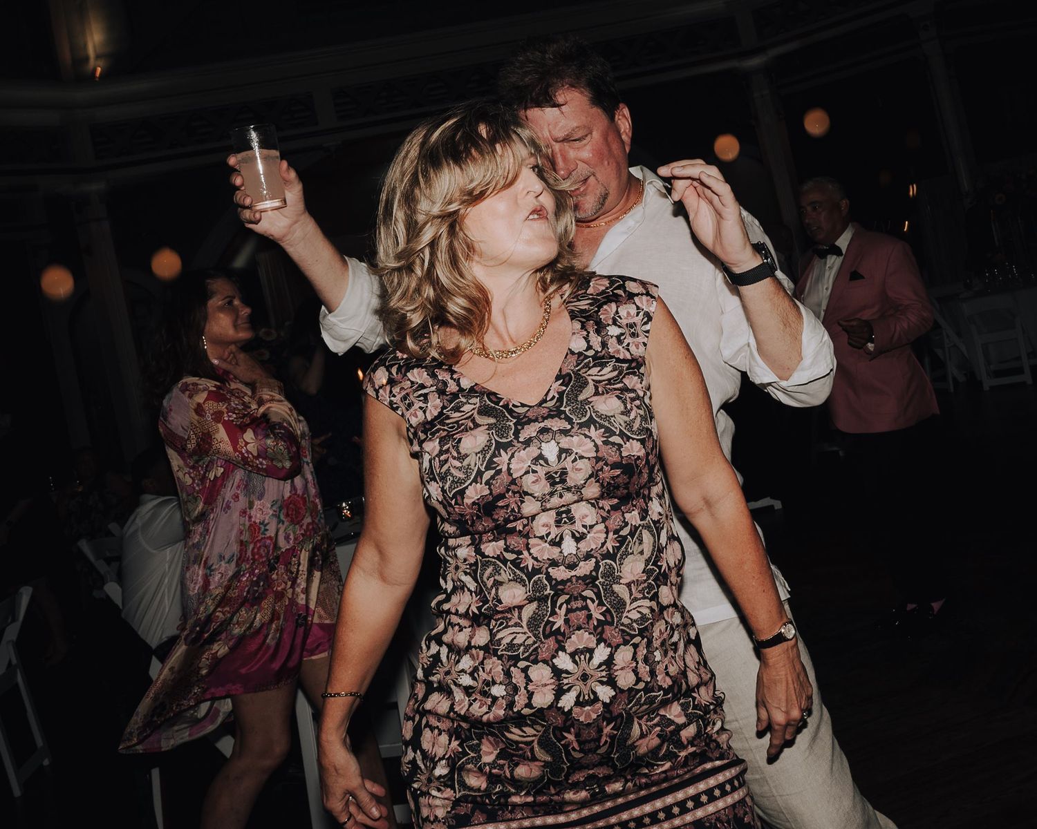People dancing and celebrating at a dimly lit indoor party venue.