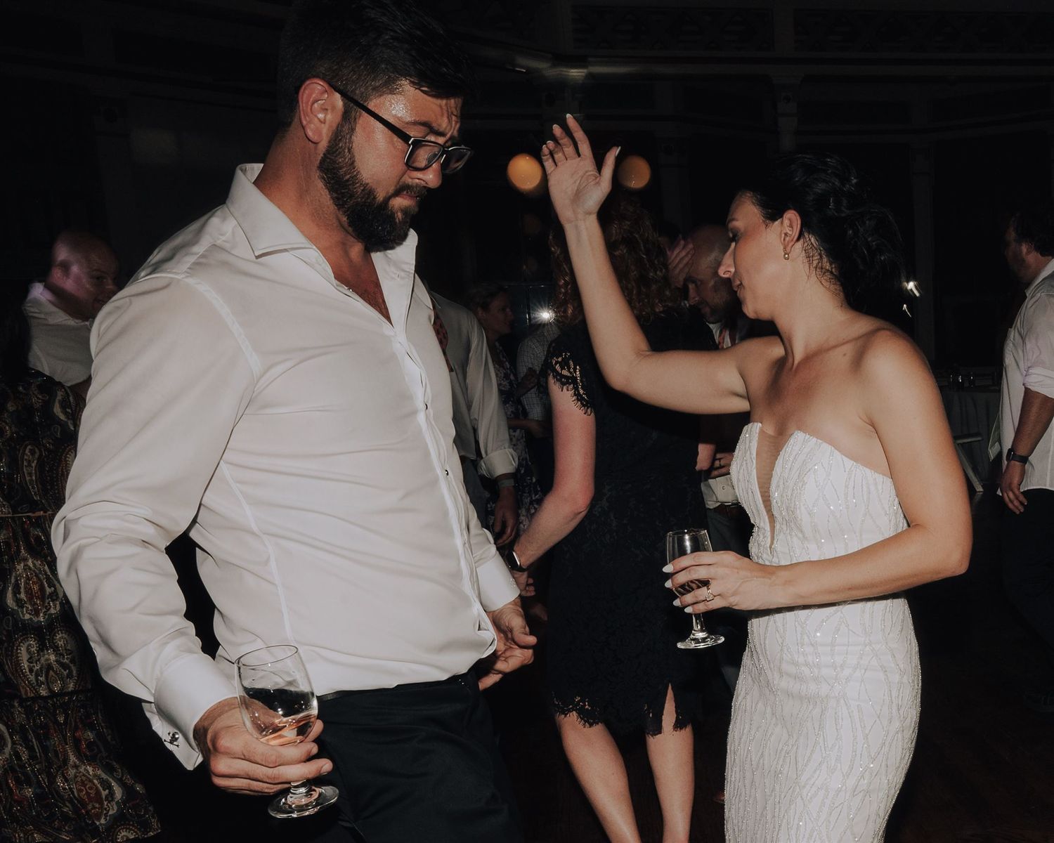 A couple dances together at a wedding reception on a wooden dance floor.