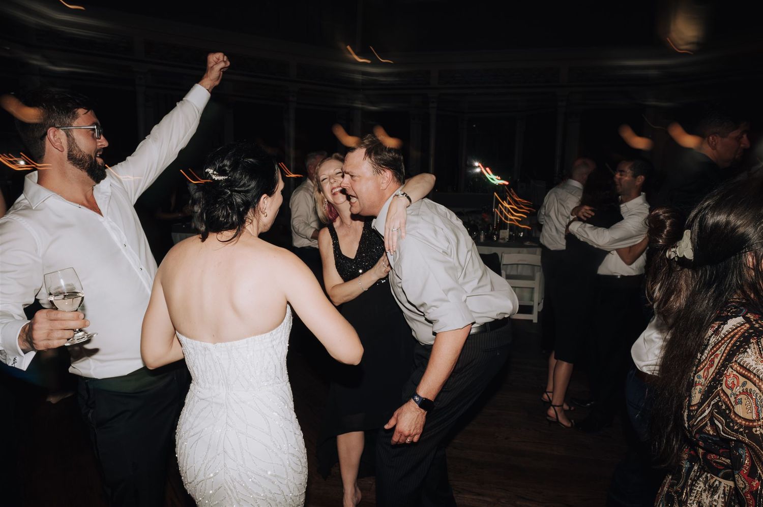 Guests dancing and celebrating on a dark wooden dance floor at an evening event.