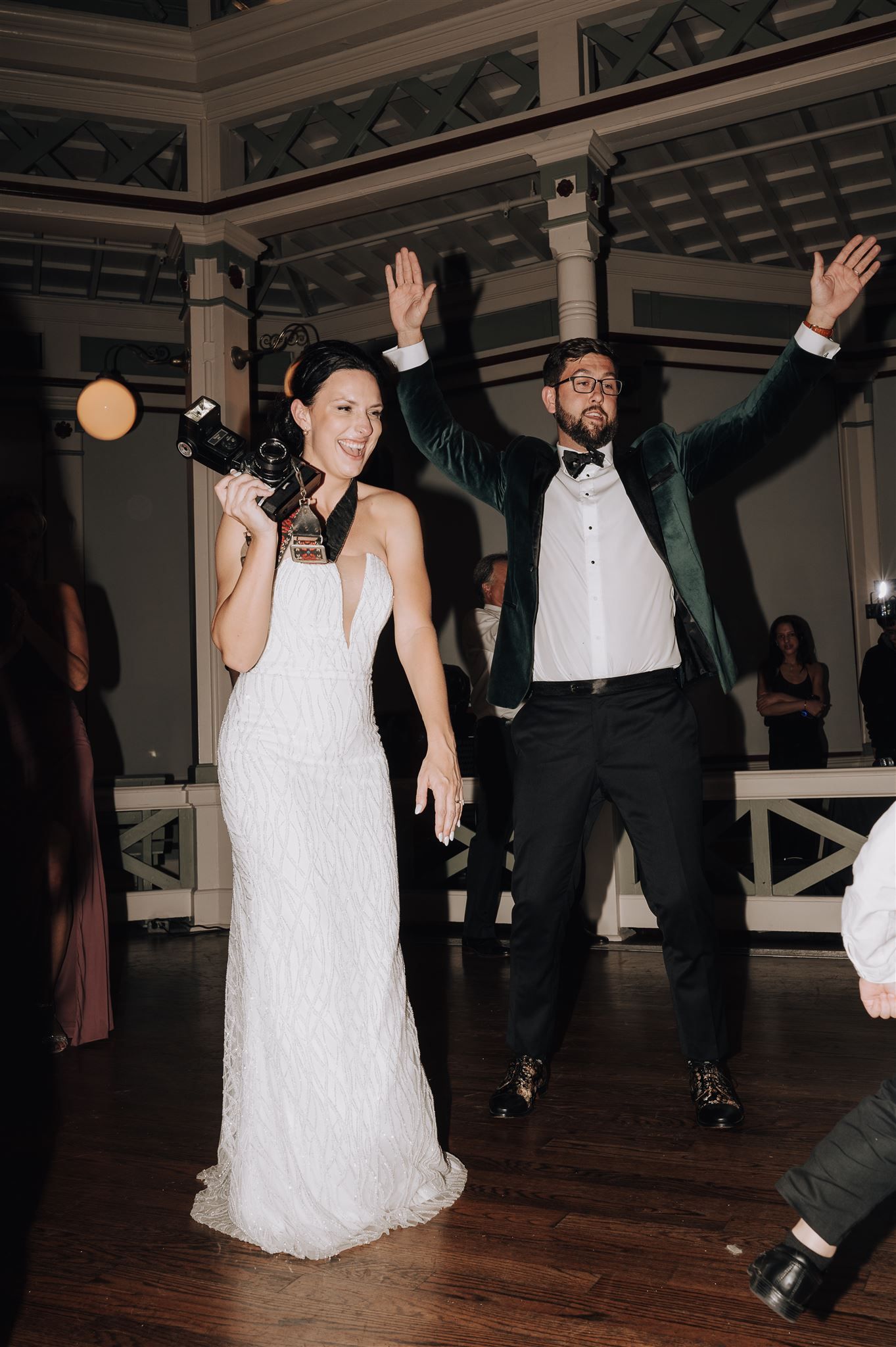 Newlyweds celebrating with raised arms during their first dance at the reception.