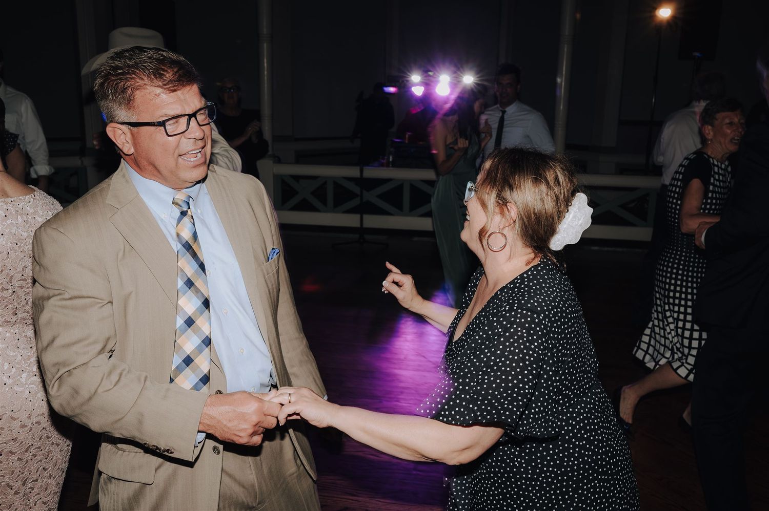 Two people engaged in playful conversation during a dance at an evening event.