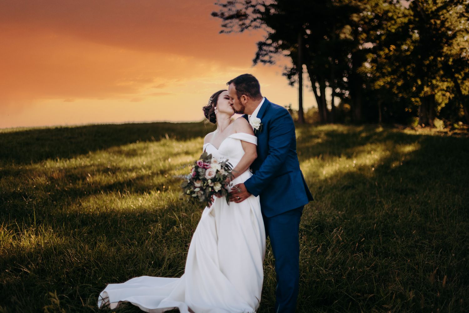 bride and groom share a kiss in a field