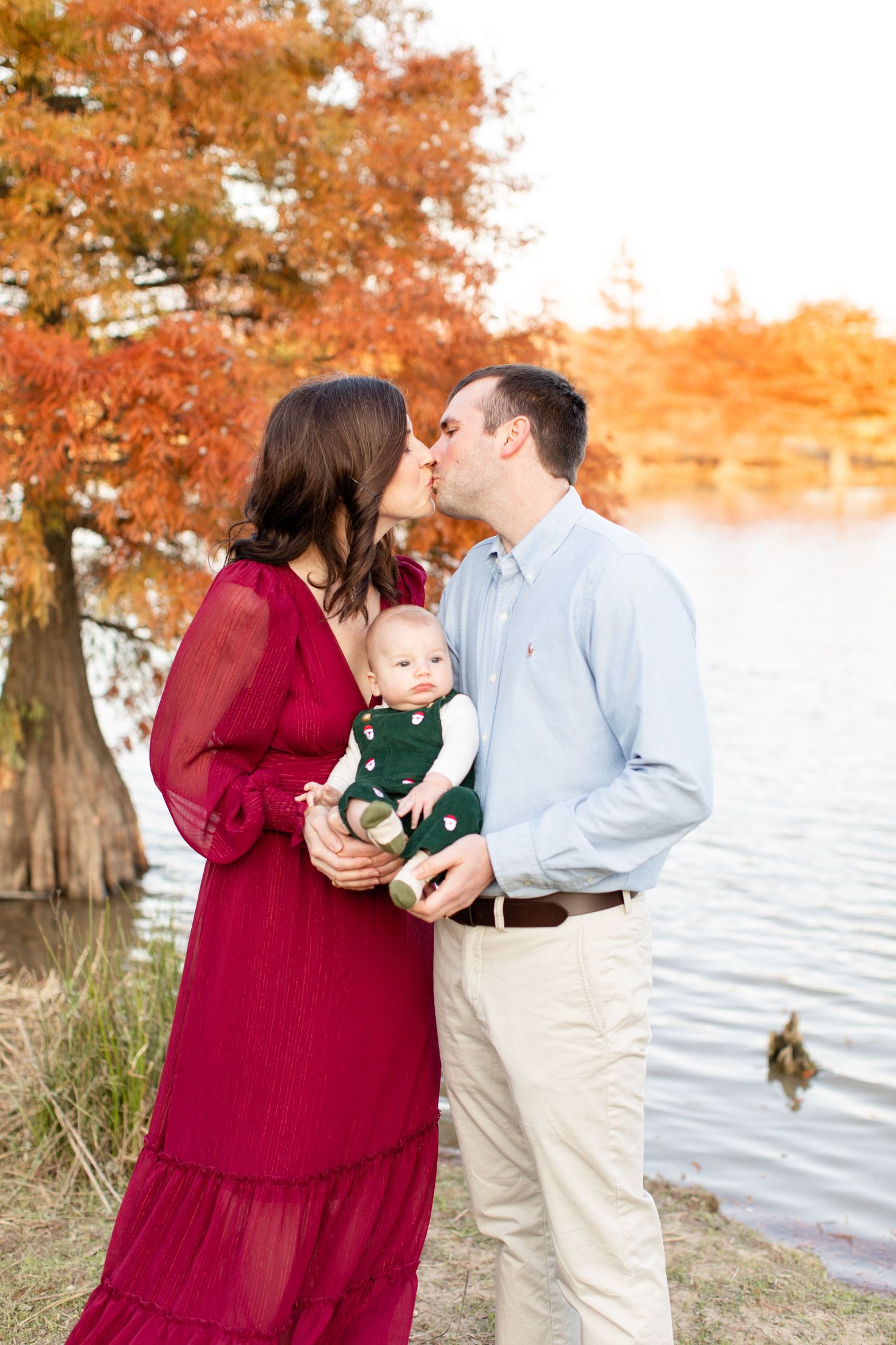 Sweet family moment captured by the water with autumn colors and cypress trees.