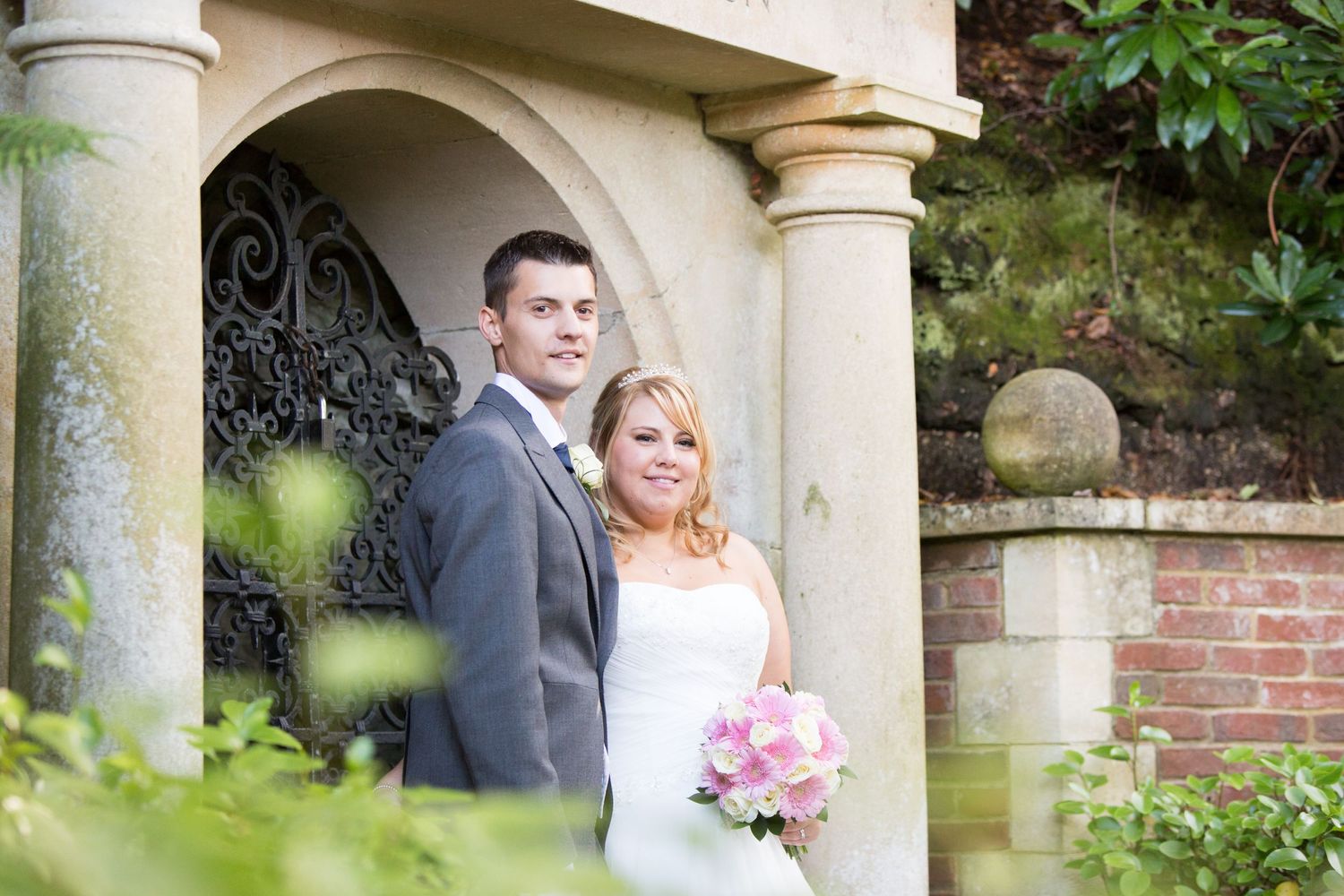 Wedding portraits taken under stone archways in a garden setting.