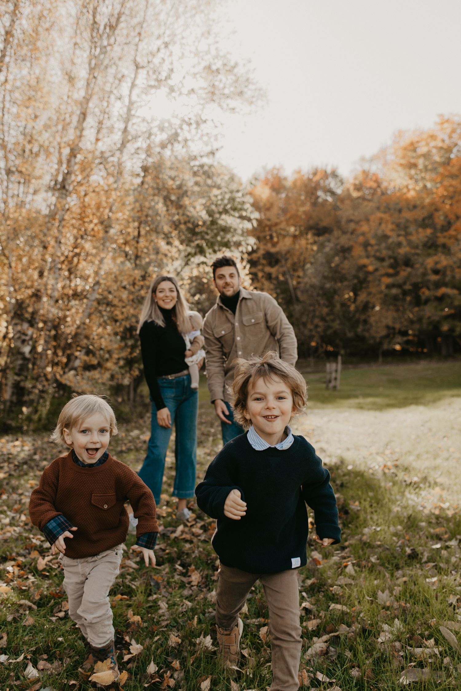 Children playing and running through autumn leaves in a sunny field.
