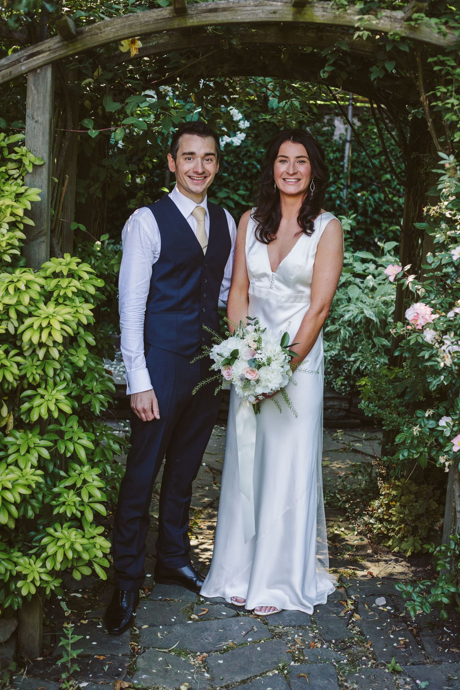 A couple poses in a lush garden setting during their wedding photoshoot.