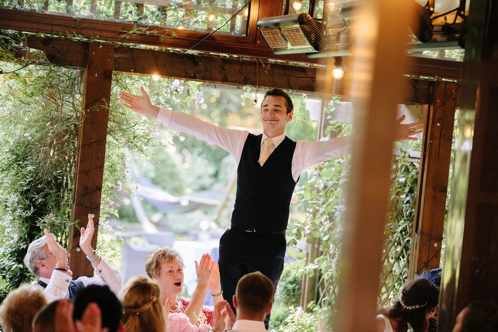 Groom stood on a chair with arms in the air