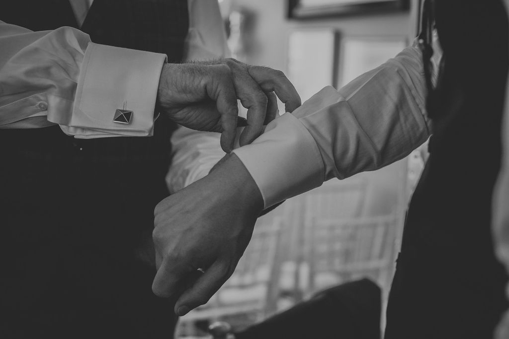 Groom putting cufflinks on