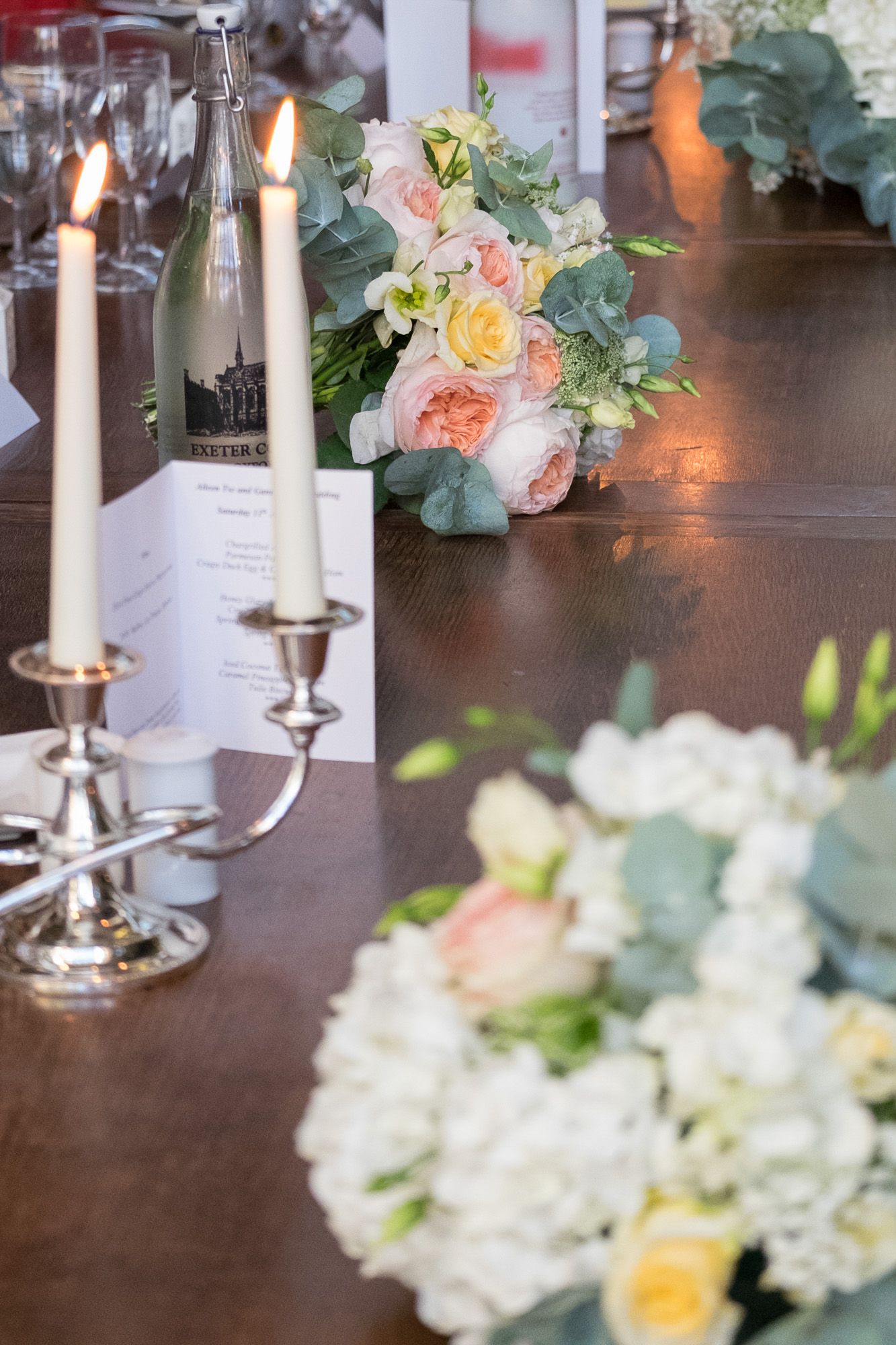 top table wedding arrangement featuring flowers, candles and menu card