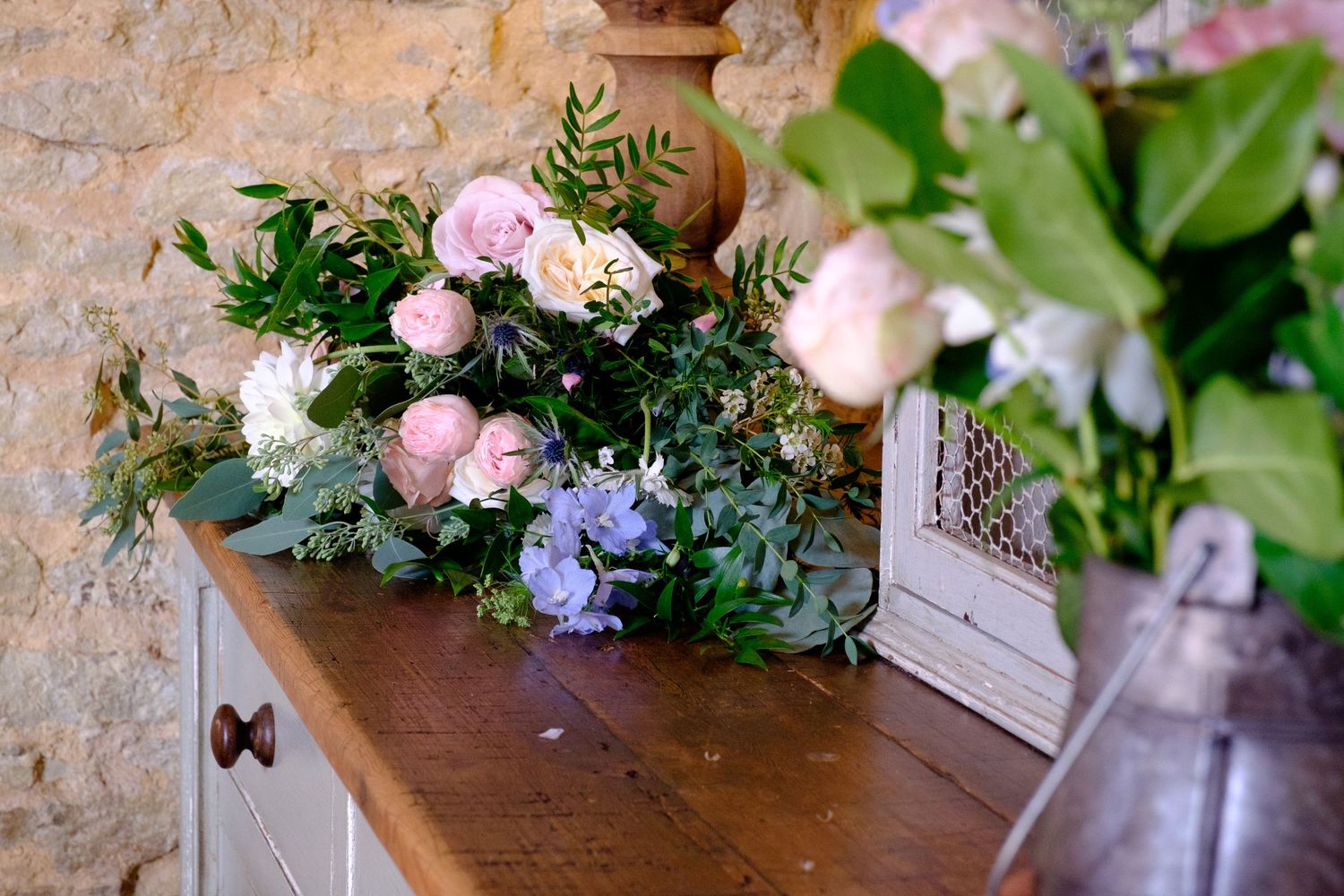 wedding flowers on antique dresser in stone barn made of cotswold stone Oxfordshire
