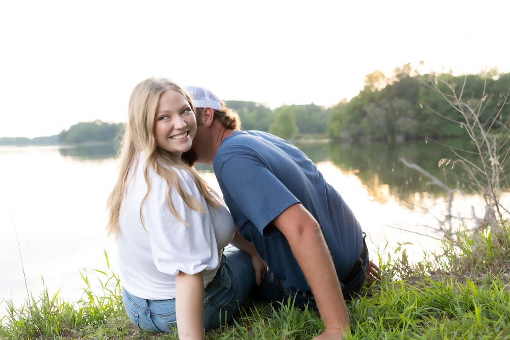 A playful couple interacting by the waterside on a sunny afternoon.