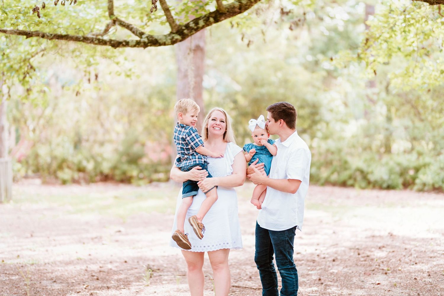 Family walks together on a sunlit path during an outdoor portrait session.