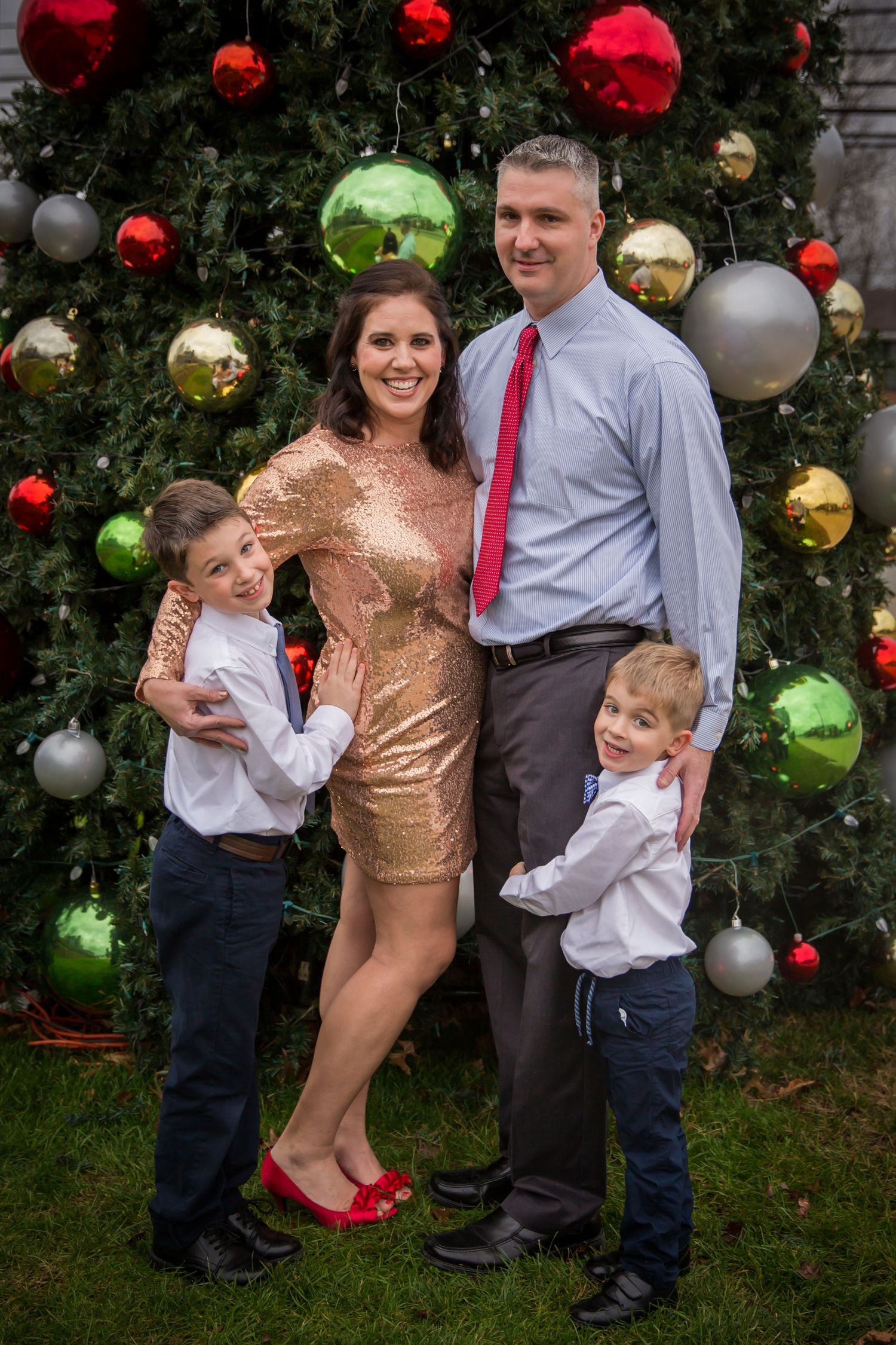 family christmas photo with dad mom and two boys wearing gold sequin dress and red high heels