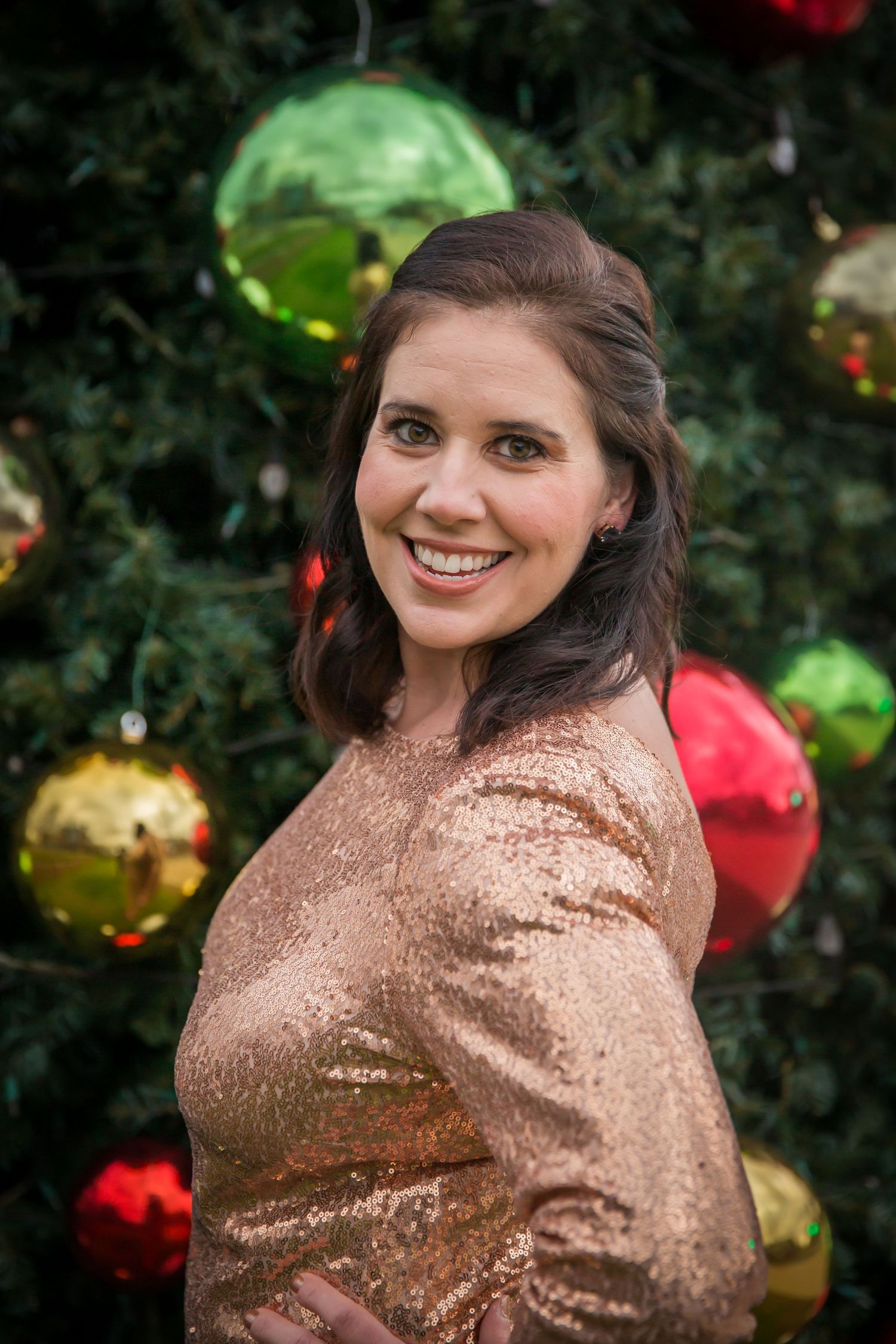 gold sequin dress in front of large christmas tree