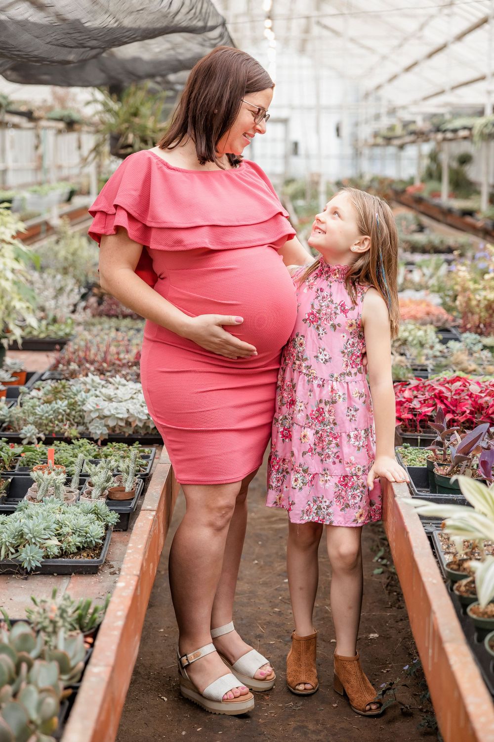 Mother and daughter share a moment together in greenhouse surrounded by succulents and plants.