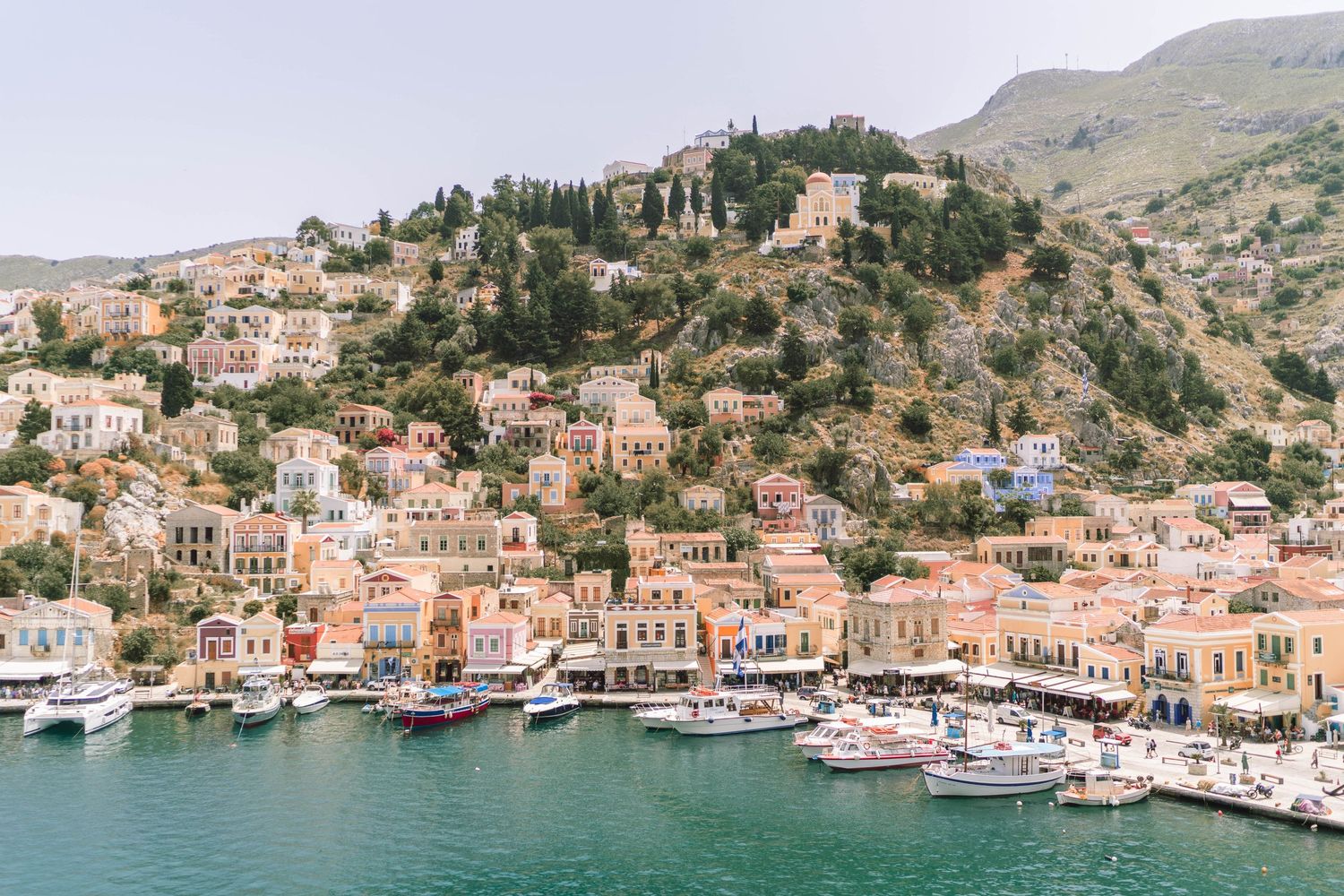 Panoramic view of a Mediterranean coastal village with colorful buildings nestled in hillside.
