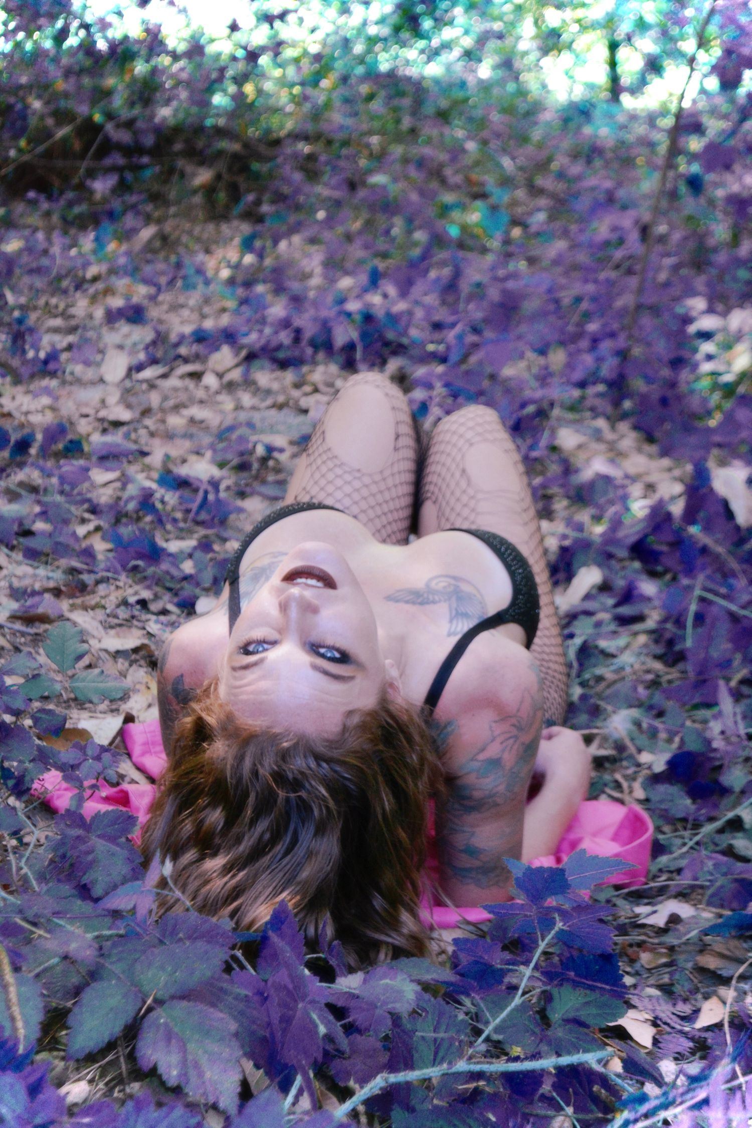Artistic portrait of person lying among purple autumn leaves.