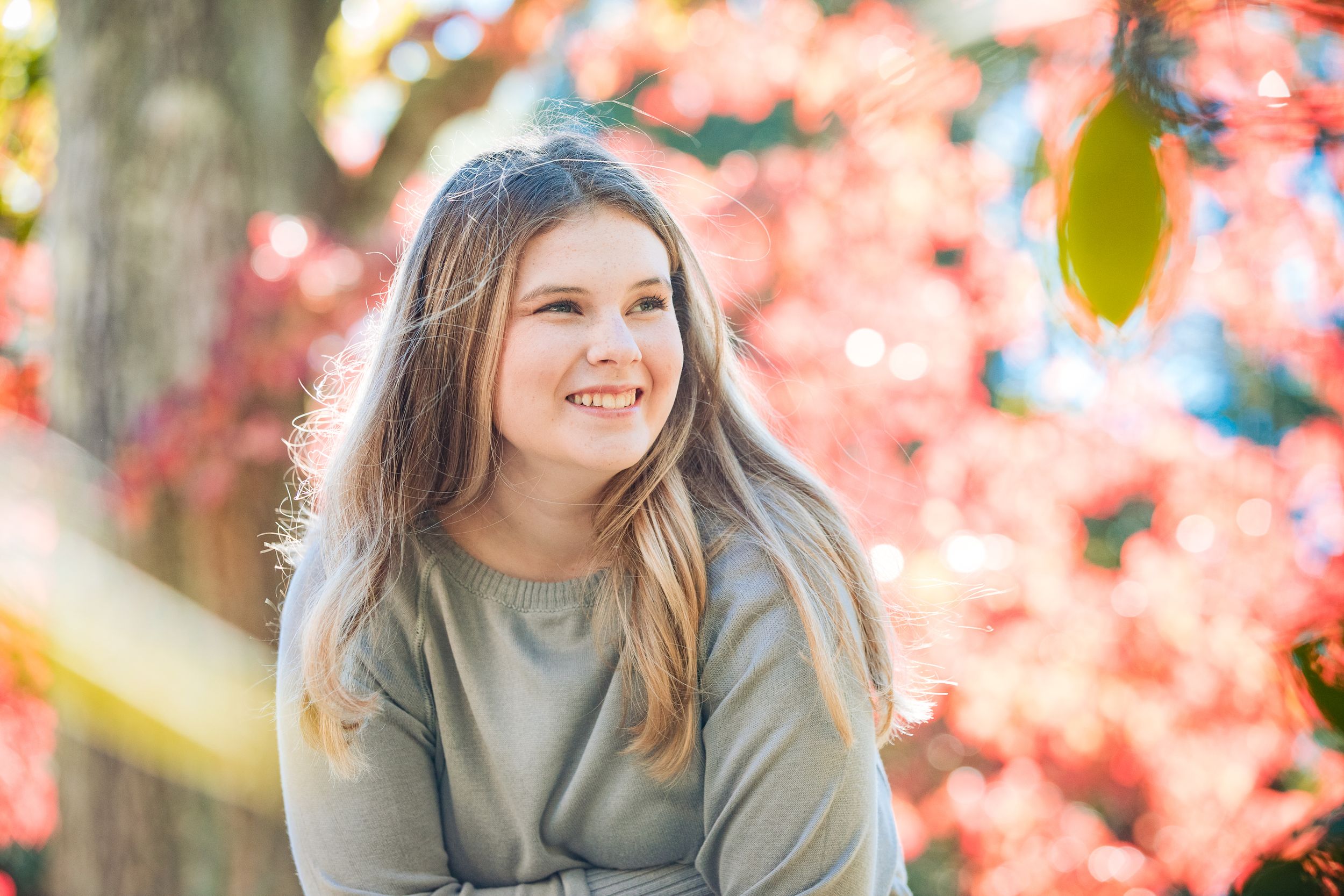 Portrait outdoors with vibrant pink cherry blossoms in soft focus background.