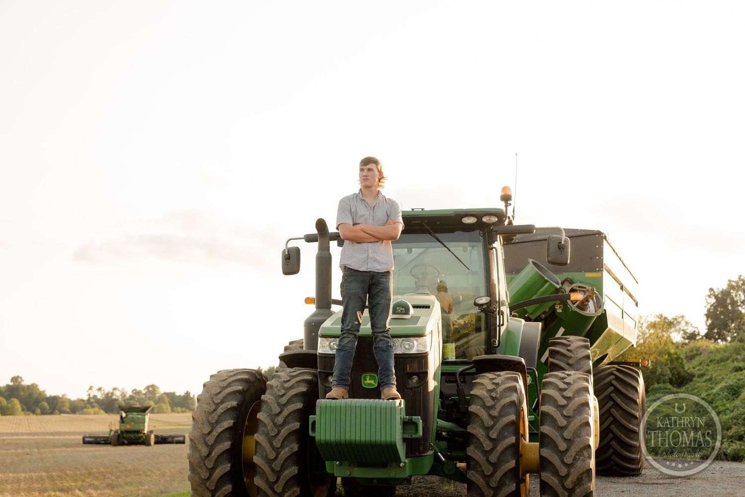 Large green John Deere tractor photographed in golden evening light on farm.