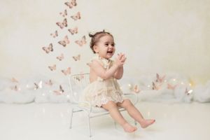 Cute baby enjoying a cake smash session on their first birthday, surrounded by BUTTERFLY decorations