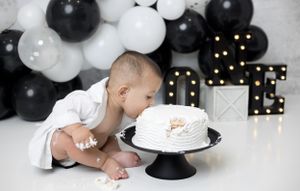 Adorable cake smash session: Baby gleefully smashing a colorful cake during a fun photoshoot
