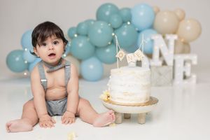 Adorable baby joyfully smashing cake during a fun and messy photoshoot