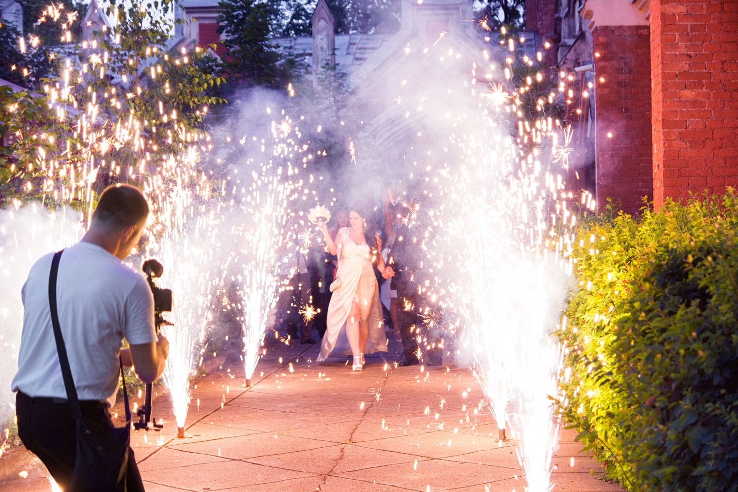 Videographer filming wedding couple walking through sparklers