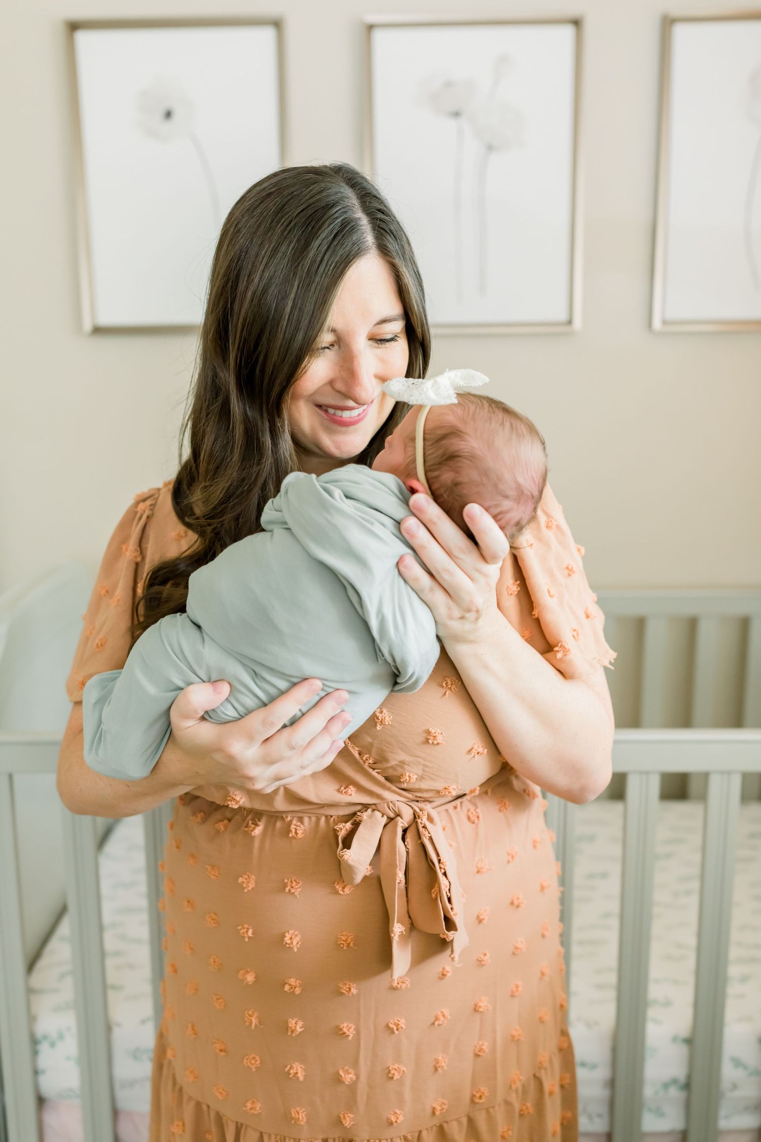 Intimate nursery scene with soft natural lighting and minimal botanical artwork on cream walls.