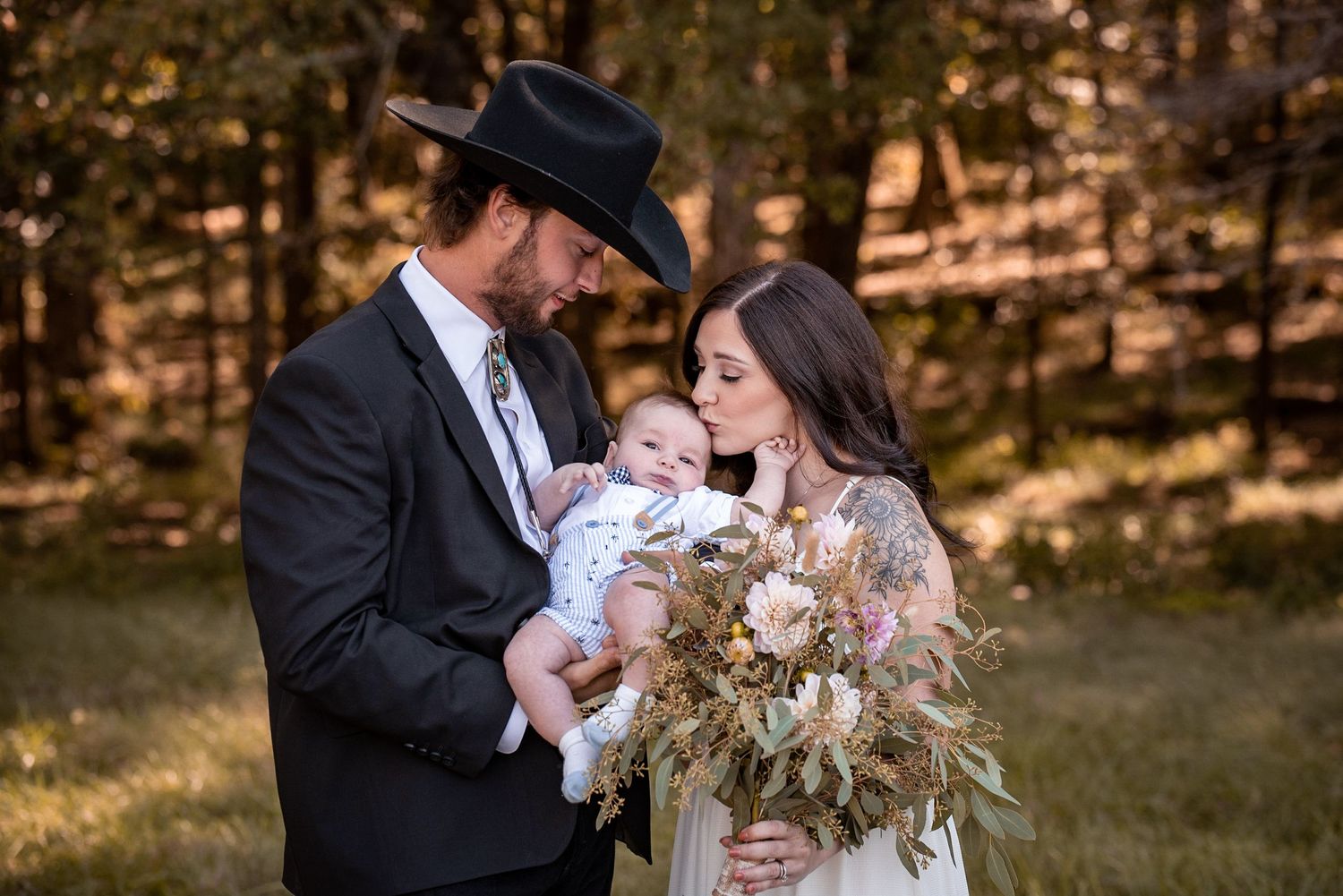 bride and groom with newborn baby on their wedding day