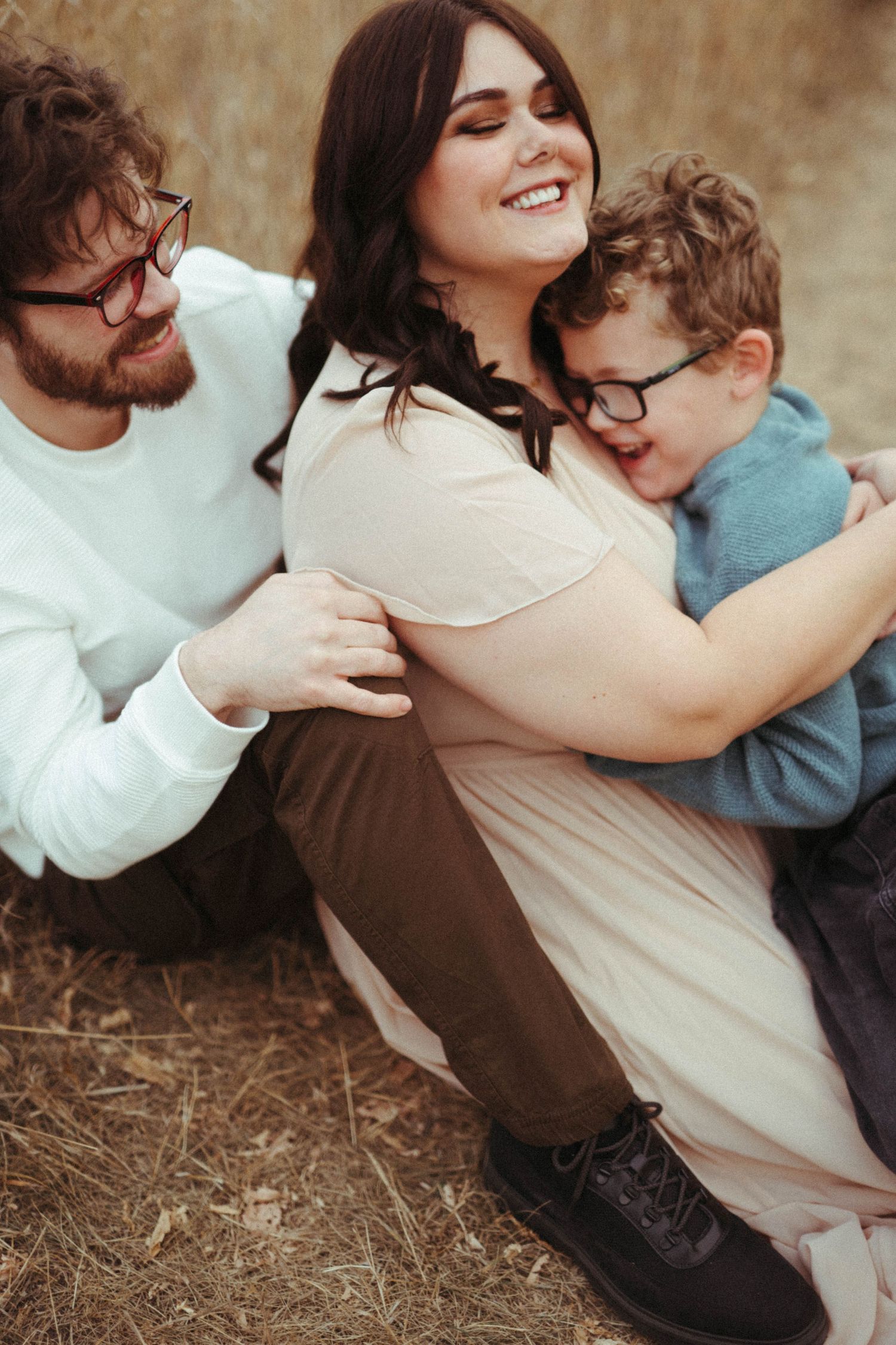 Warm family portrait outdoors showing affectionate embrace and genuine smiles.