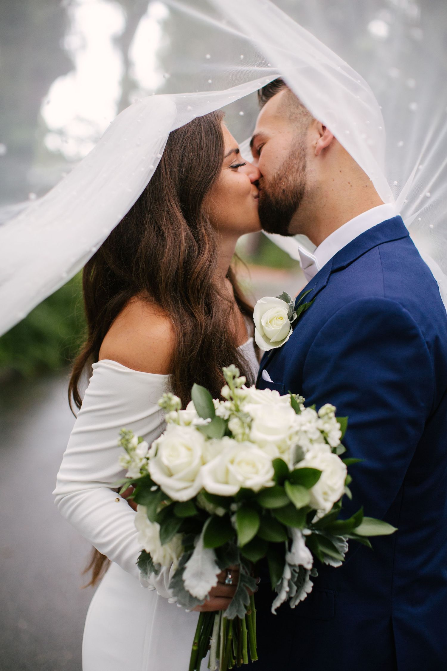 Romantic wedding portrait with white roses and flowing veil capturing an intimate moment.