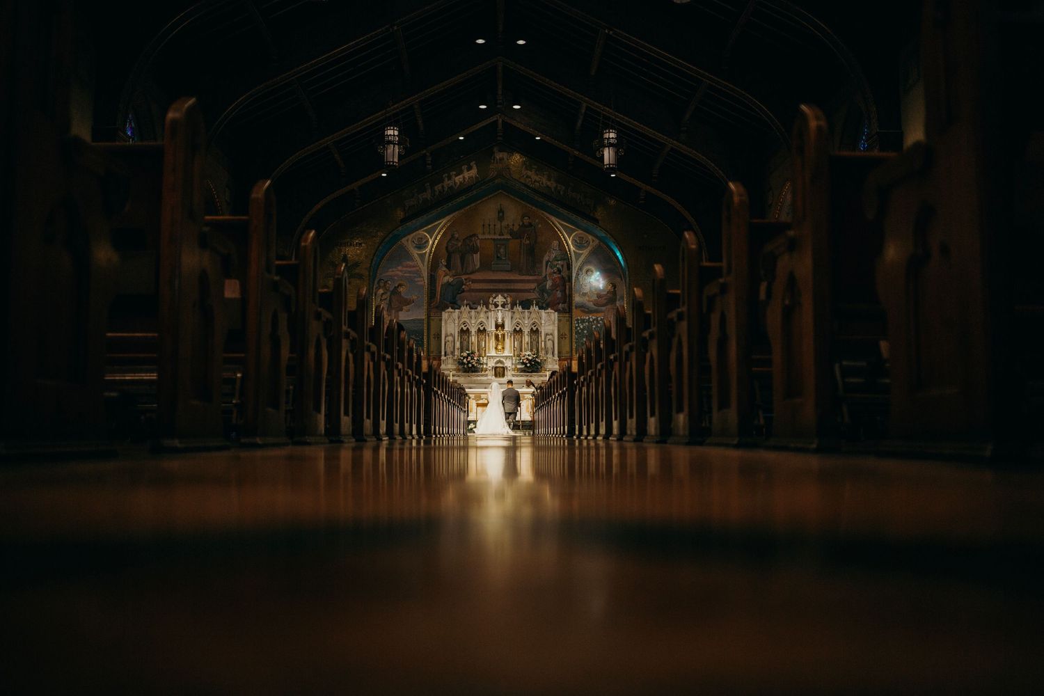 A dark cathedral interior with dramatic lighting illuminating the center aisle.