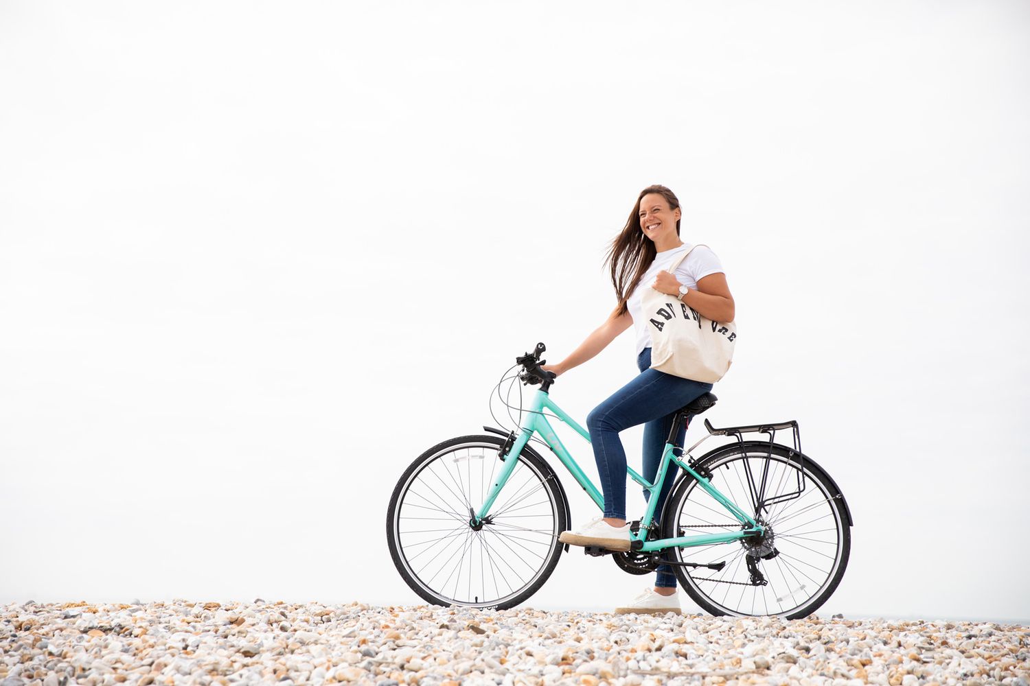 Cyclist riding a turquoise beach cruiser bicycle on a minimalist white background during business branding photoshoot.