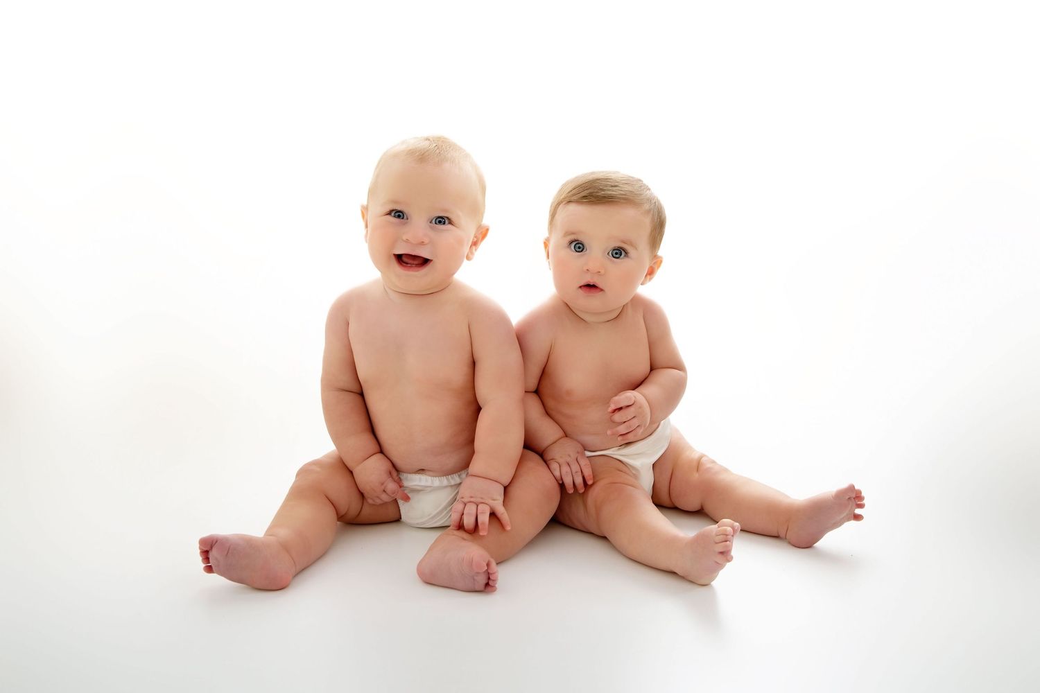 Series of adorable babies sitting together in white studio setting.