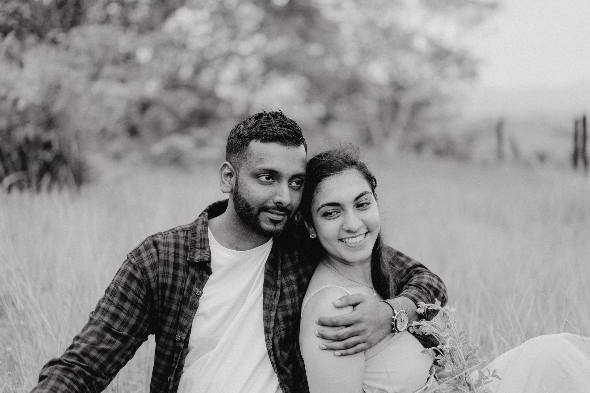 Couple in casual attire sitting together in a grassy outdoor setting.