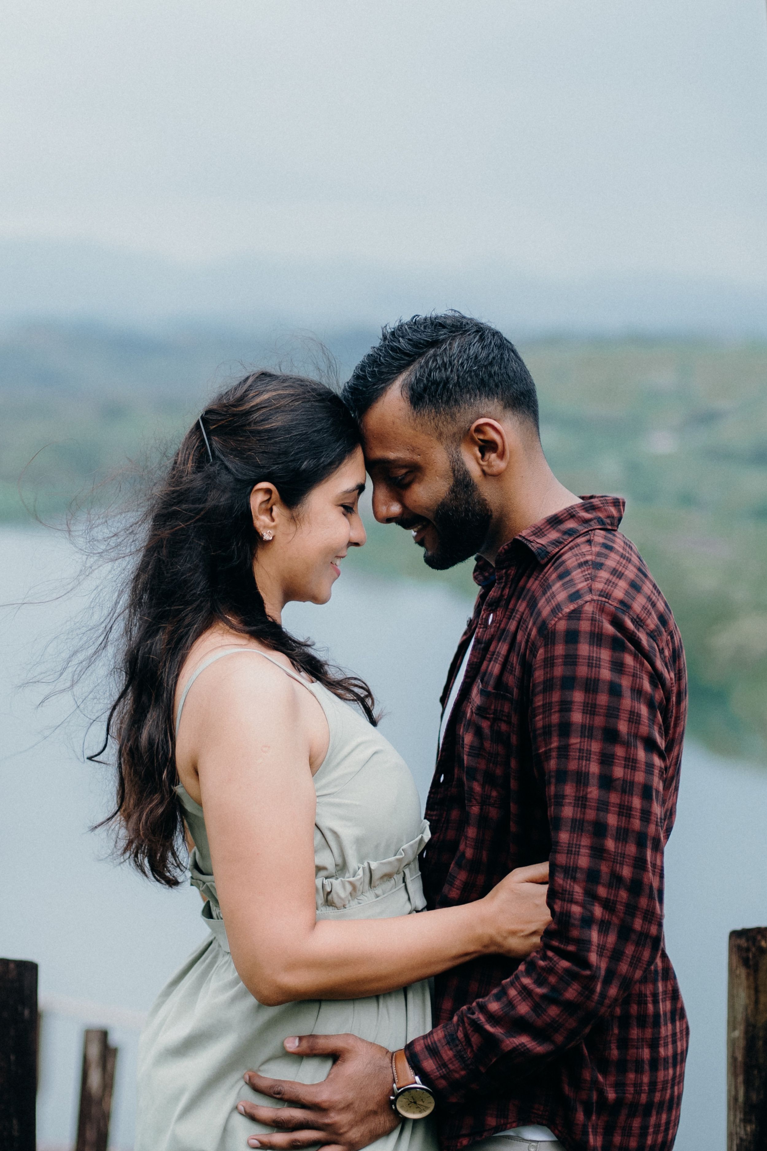 An intimate moment captured between two people against a misty mountain backdrop.