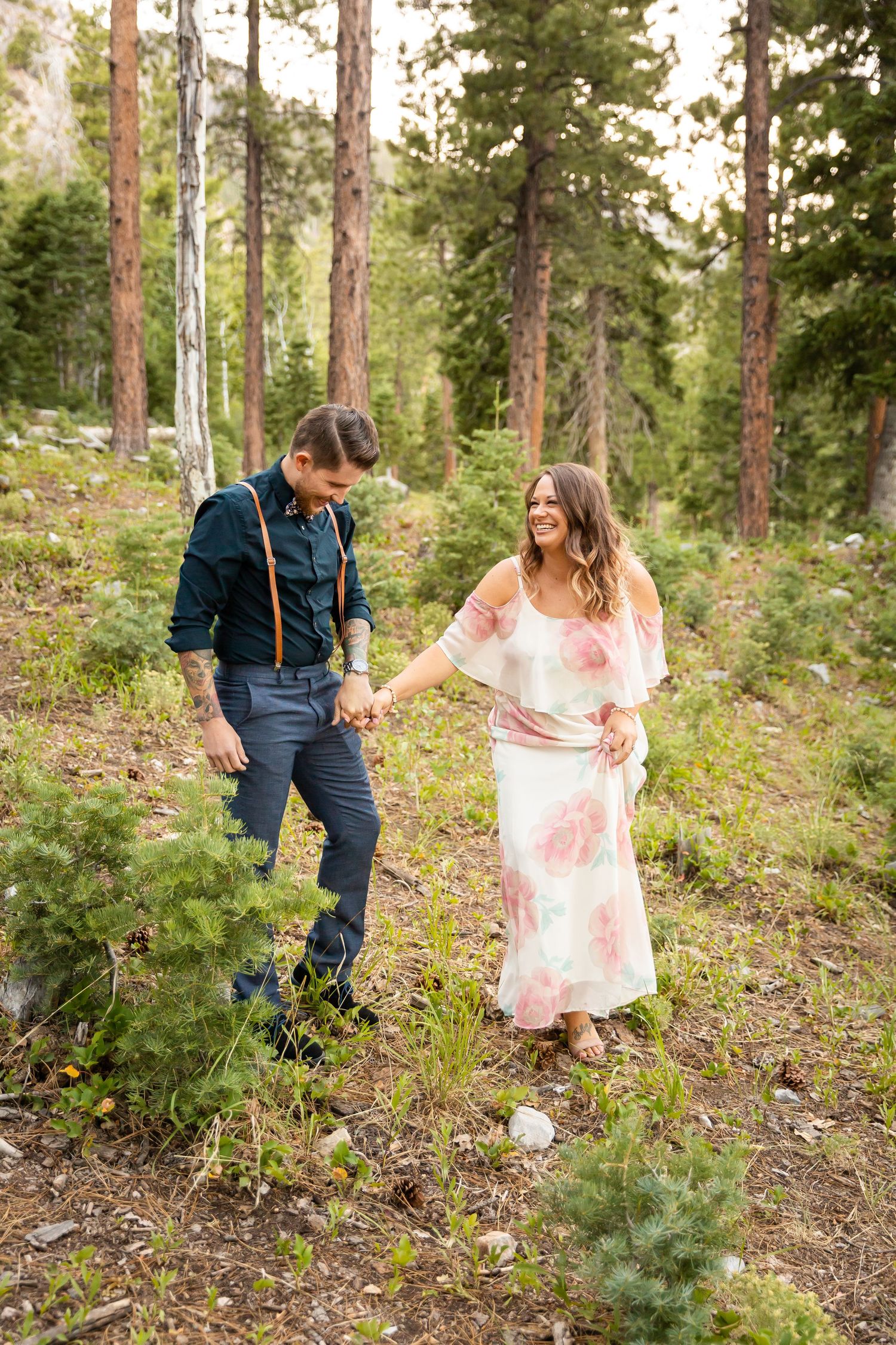 A couple enjoying a casual stroll through a pine forest during their mountain photoshoot.