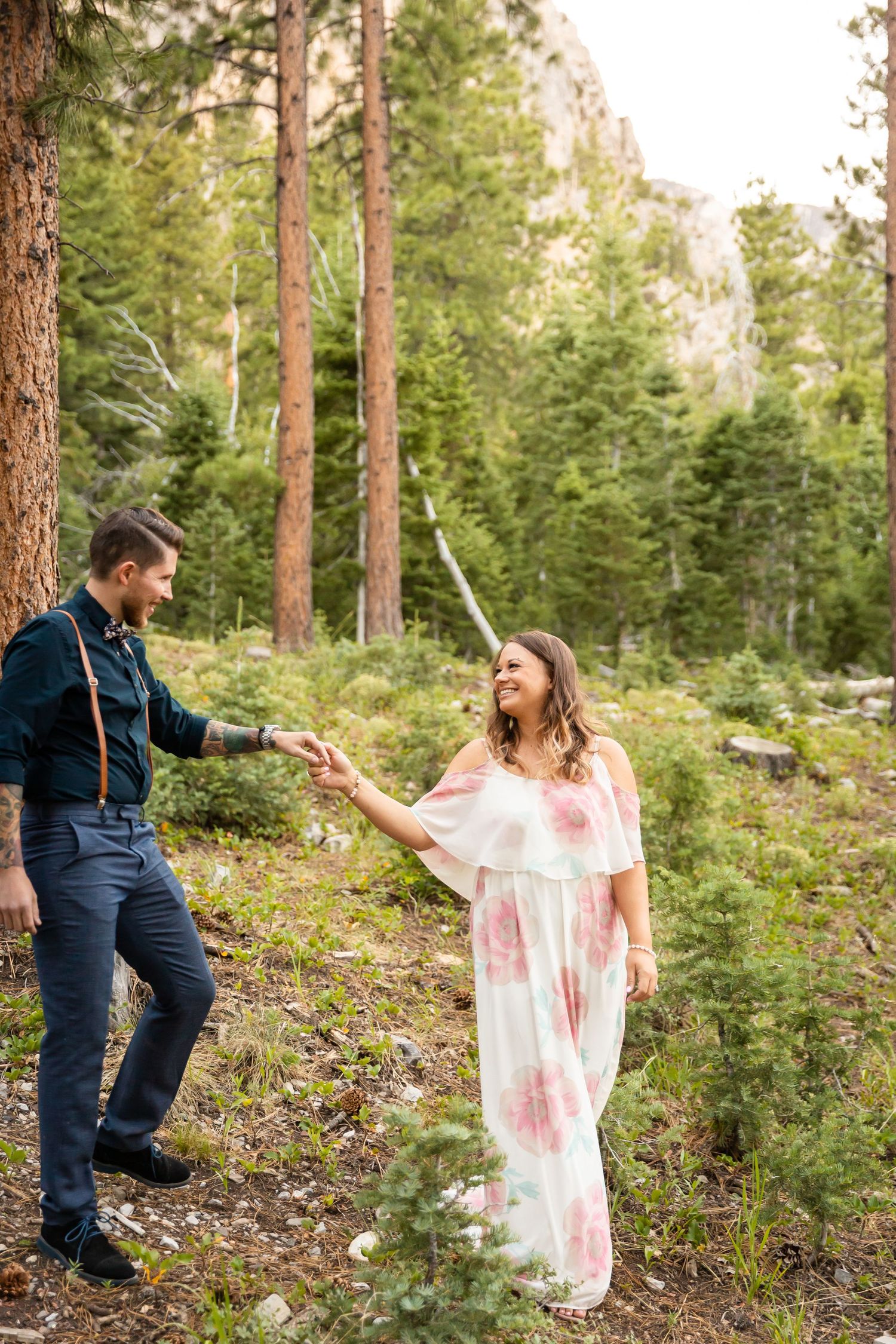 A playful moment between a couple on a wooded hillside during their outdoor photoshoot.
