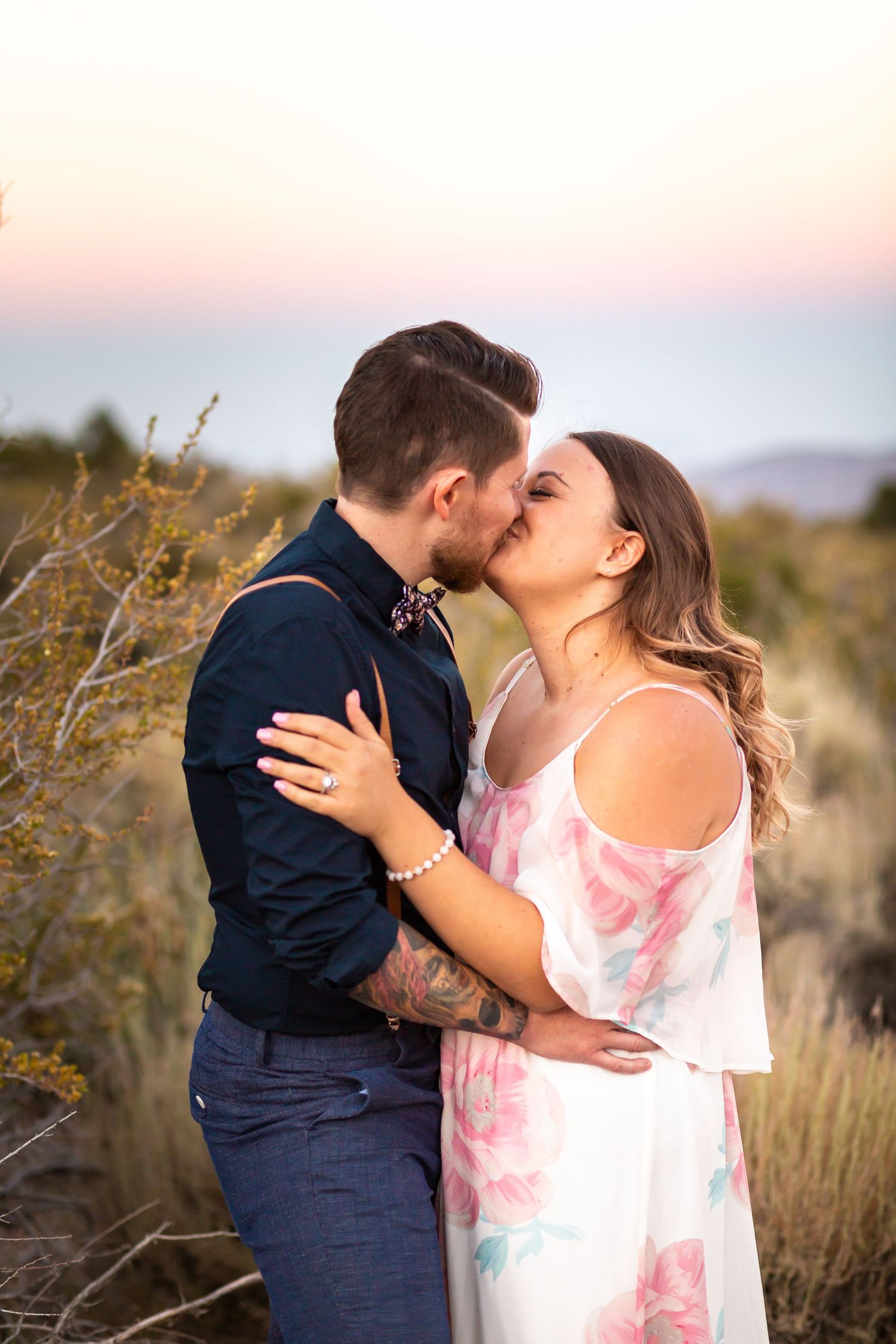 Romantic kiss captured during desert engagement photoshoot at sunset.