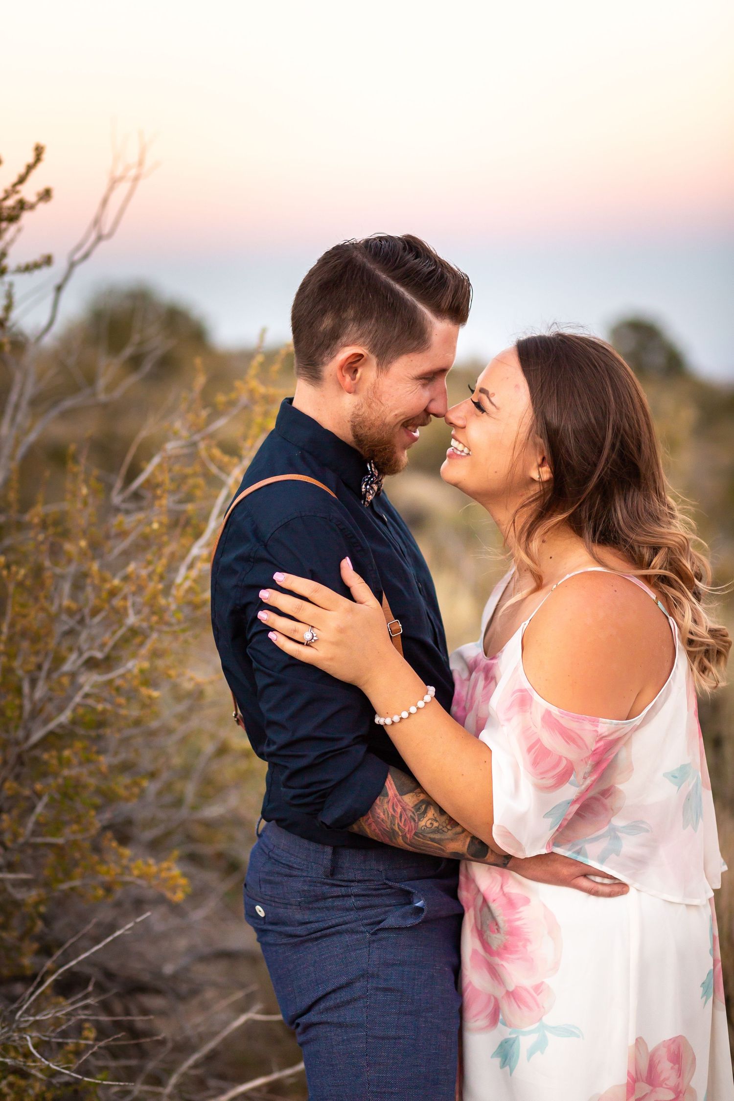 Intimate moment between couple in desert setting at dusk.
