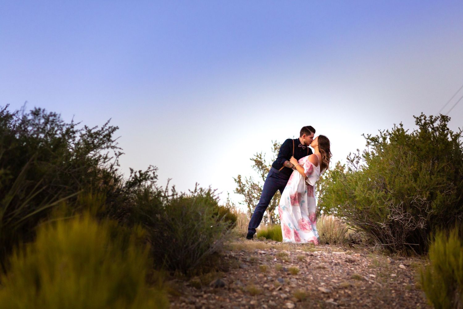 Couple embracing during sunset photoshoot in desert landscape.