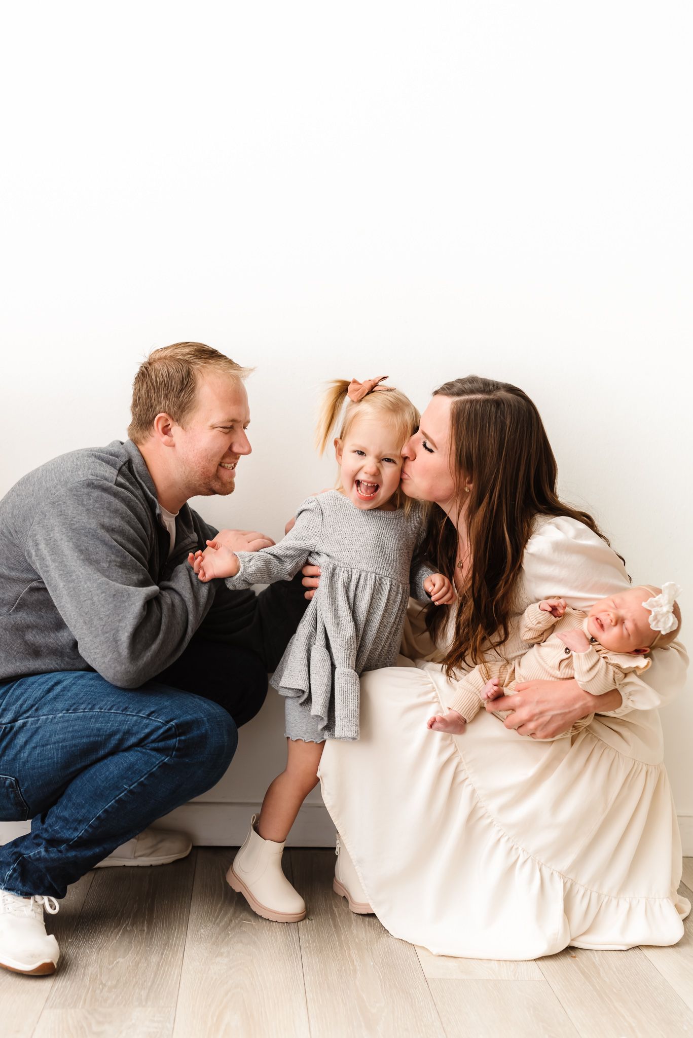 Candid family portrait series showing playful moments against a white backdrop.