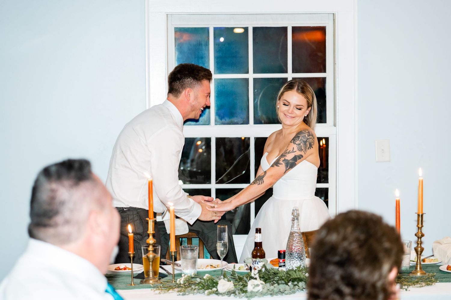 Wedding reception scene with candlelit table and cake cutting celebration.
