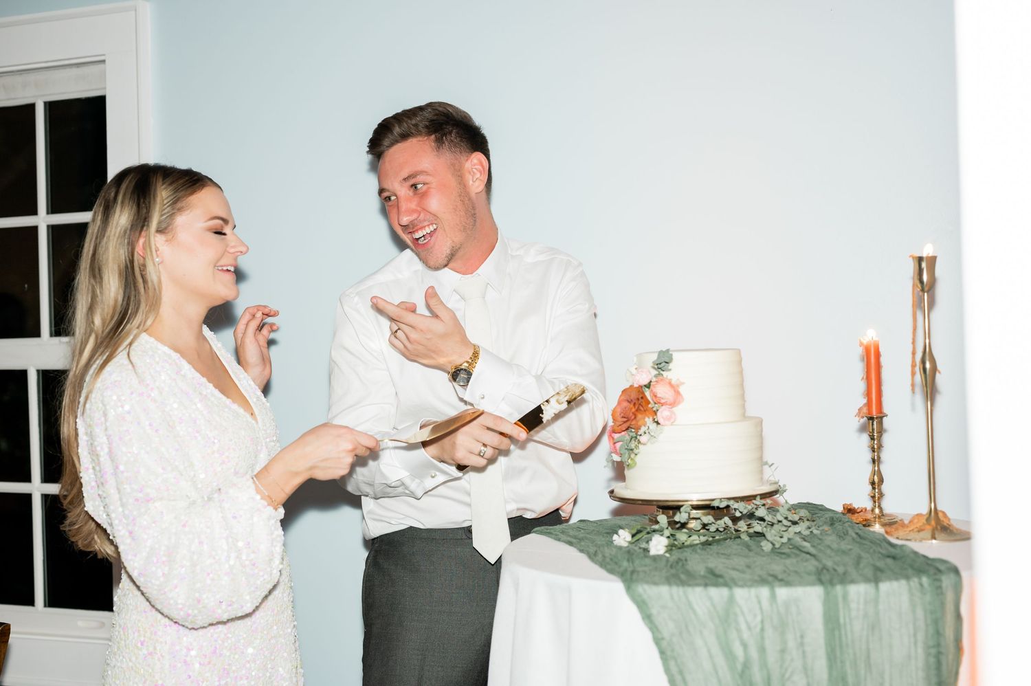 Wedding couple playfully feeding each other cake during their reception celebration.
