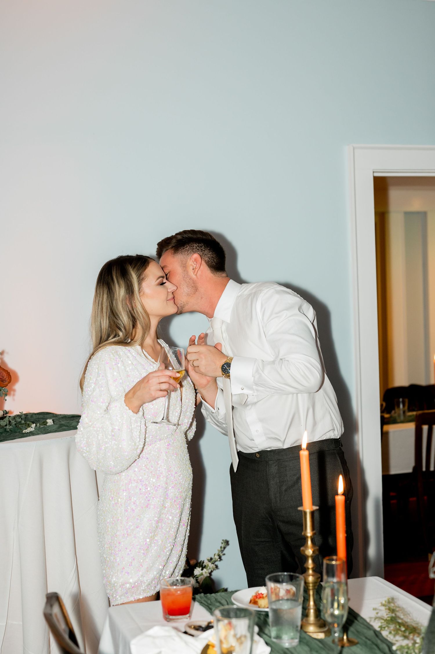 Couple sharing a romantic moment in a dimly lit room with candles and wine glasses.