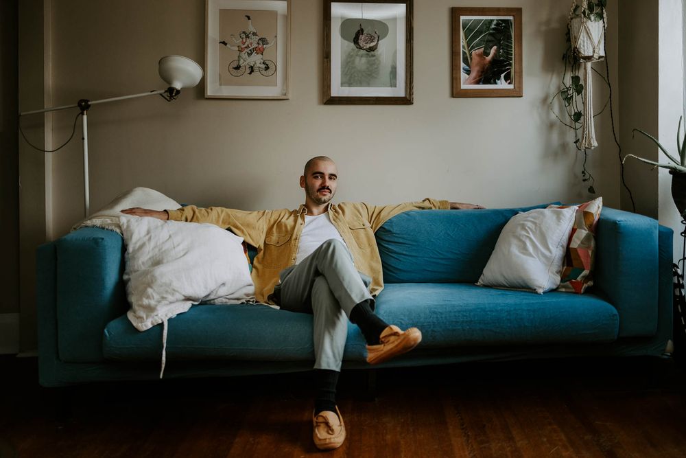 Casual lifestyle shot of someone lounging on teal sofa with wall art.