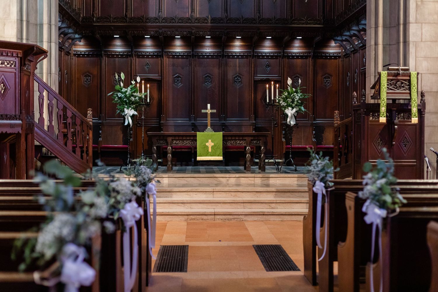 Church sanctuary with wooden paneling and decorative altar area during a wedding ceremony.