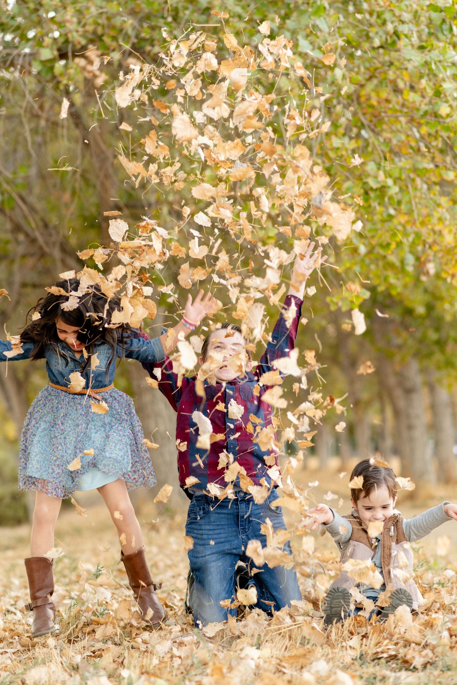 People playing and throwing autumn leaves in the air during outdoor photo session.