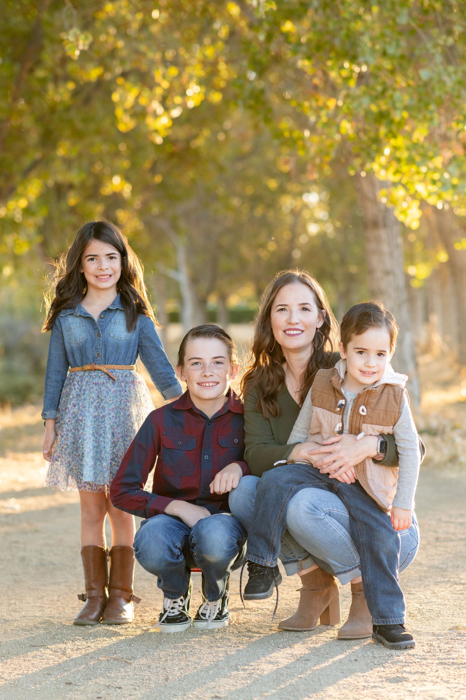 Siblings posing together on ground during autumn photoshoot with fallen leaves.