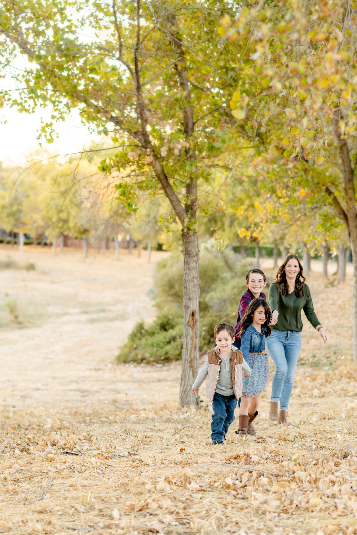 Group walking together through autumn park with fallen leaves on ground.